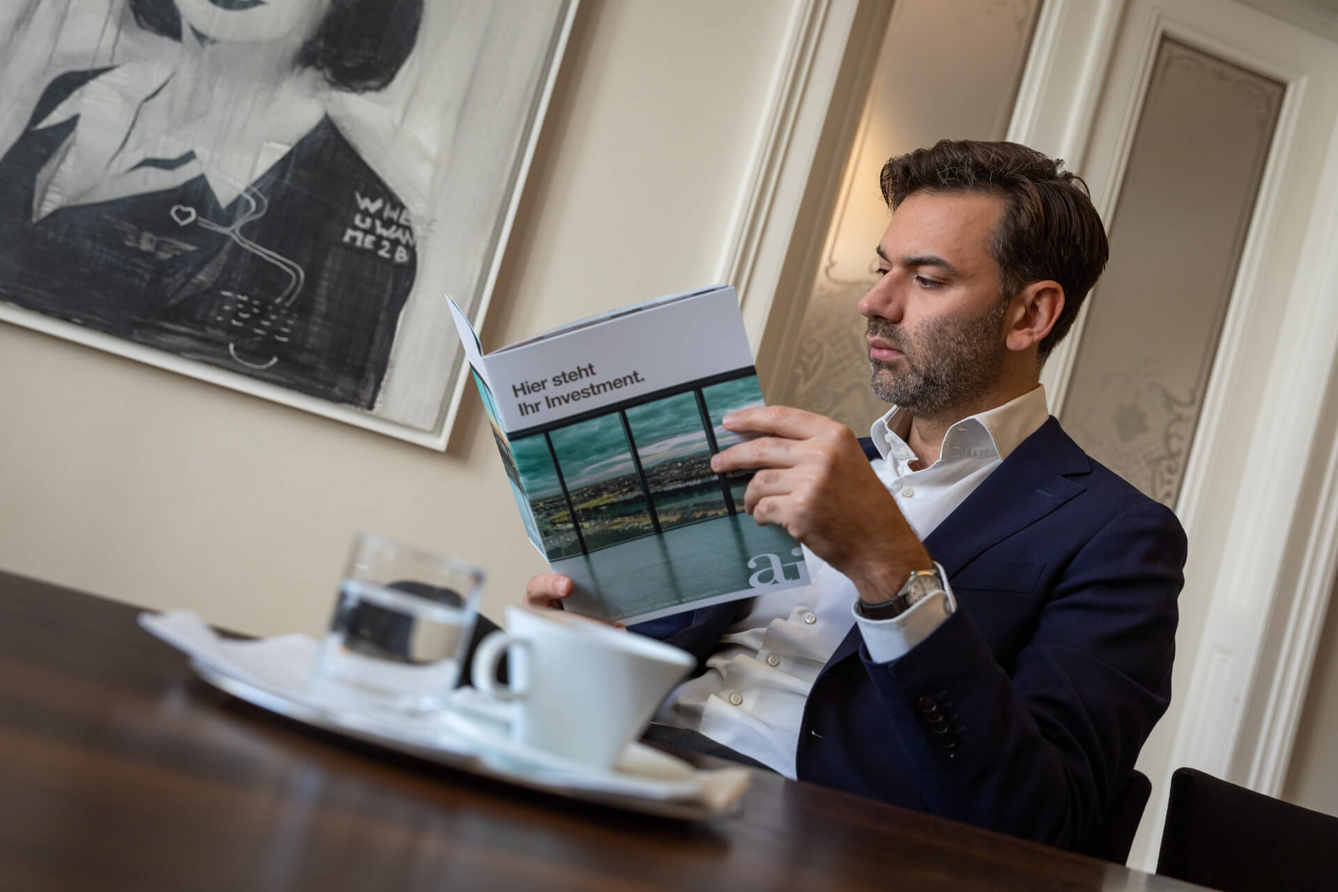 Ein Mann ließt gerade bei einem Kaffee das Zinhaus-Magazine
