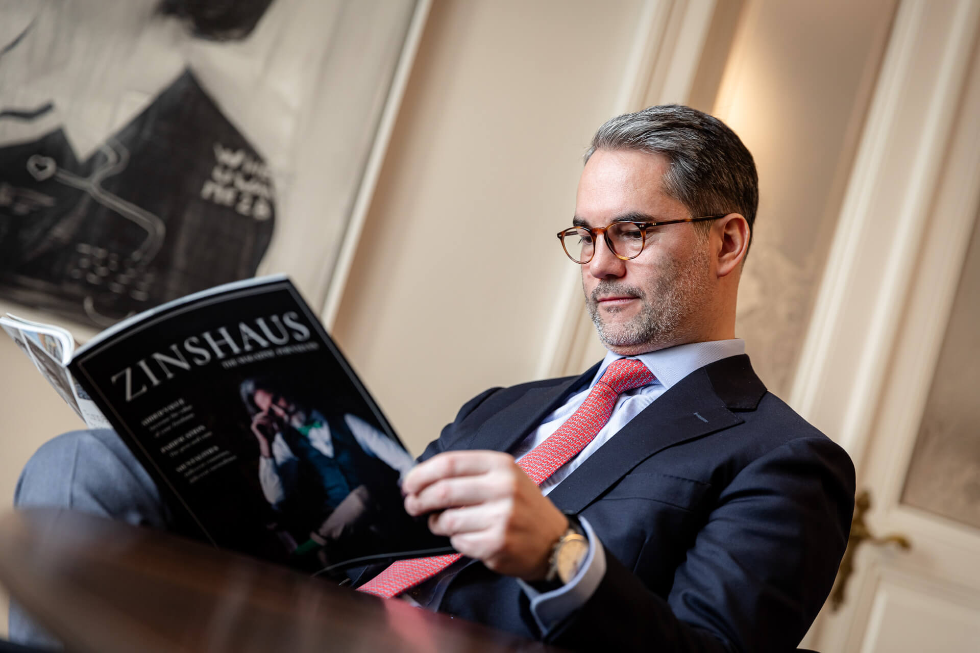 Ein Mann ließt gerade bei einem Kaffee das Zinhaus-Magazine