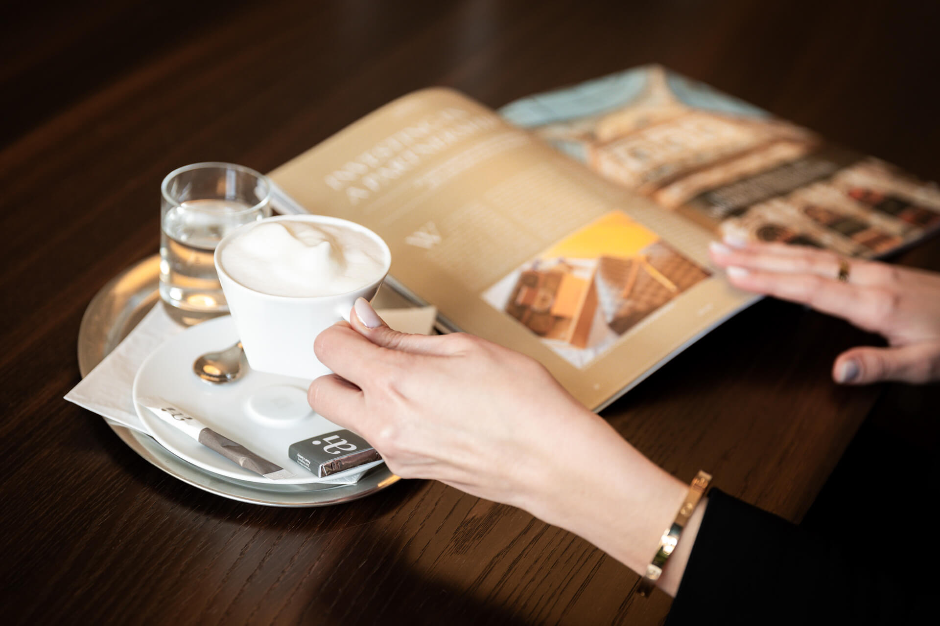 eine Hand hält einen Kaffee in Händen und man sieht das Zinshaus-Magazine
