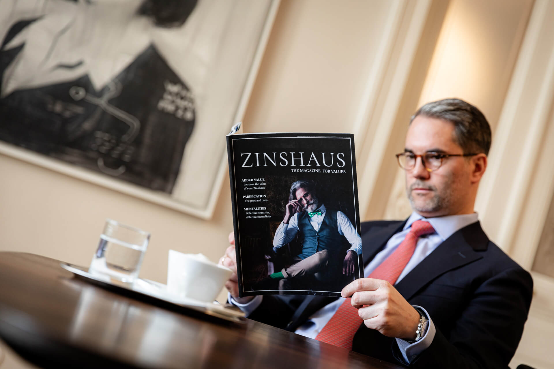 Ein Mann ließt gerade bei einem Kaffee das Zinhaus-Magazine