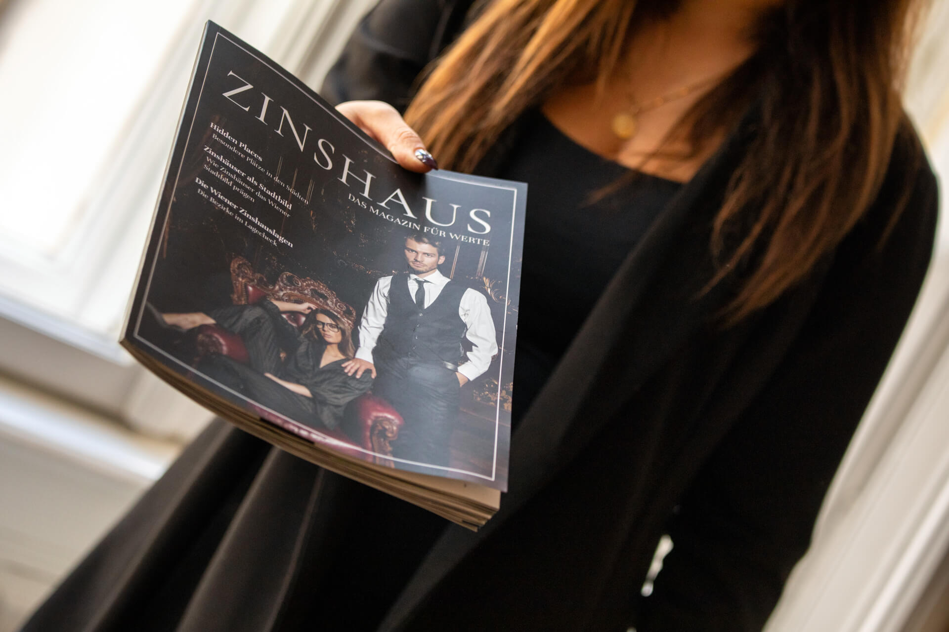eine Hand überreicht das Zinshaus-Magazine von Arnold Immobilien