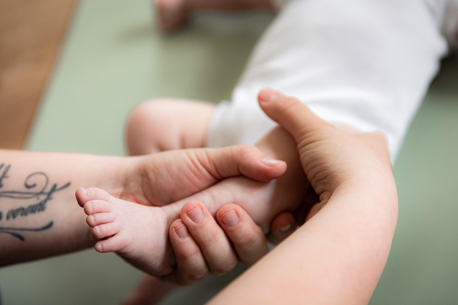 An einem Baby wird eine Babymassage an dem Bein vorgezeigt.
