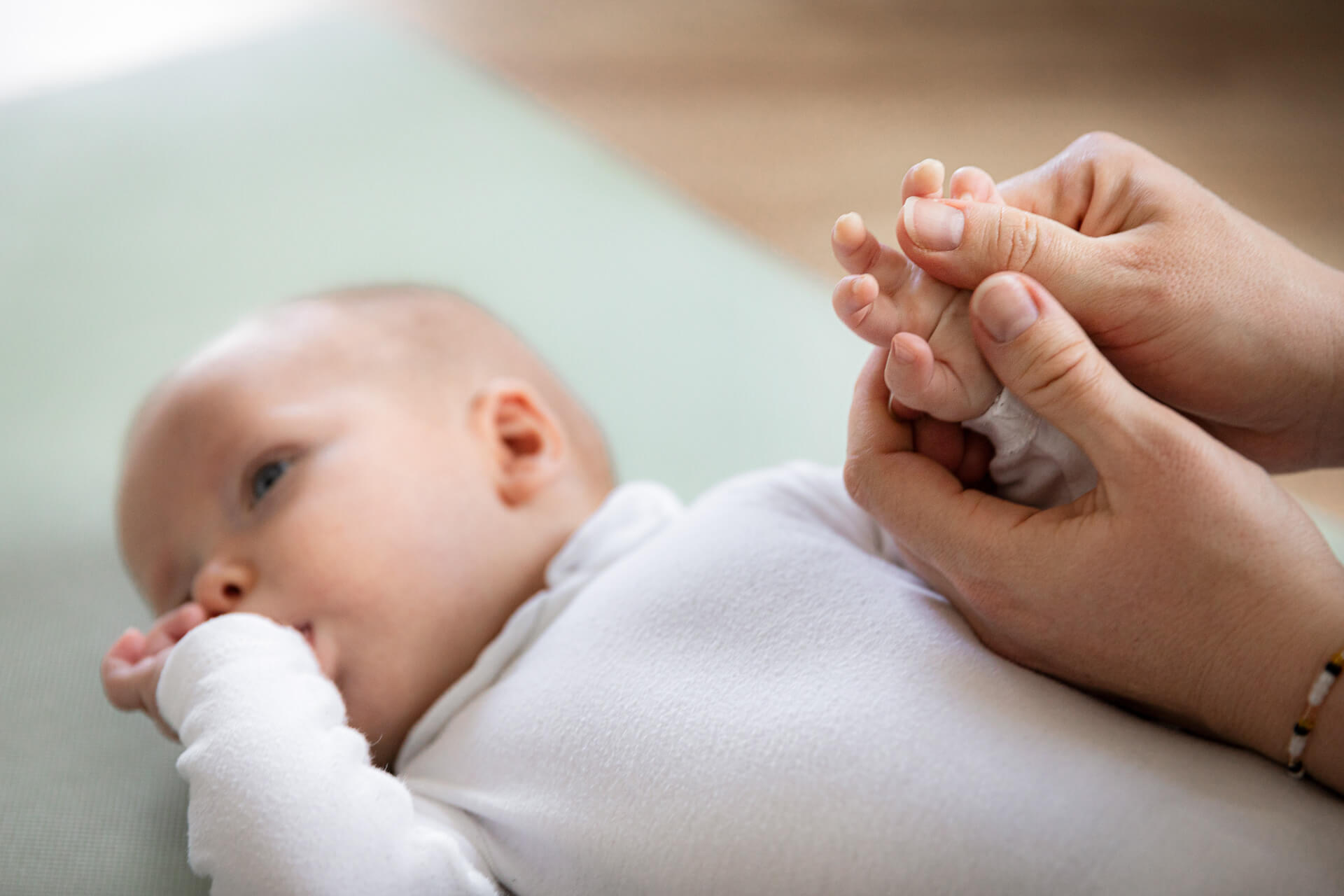 An einem Baby wird eine Babymassage an der Hand vorgezeigt.