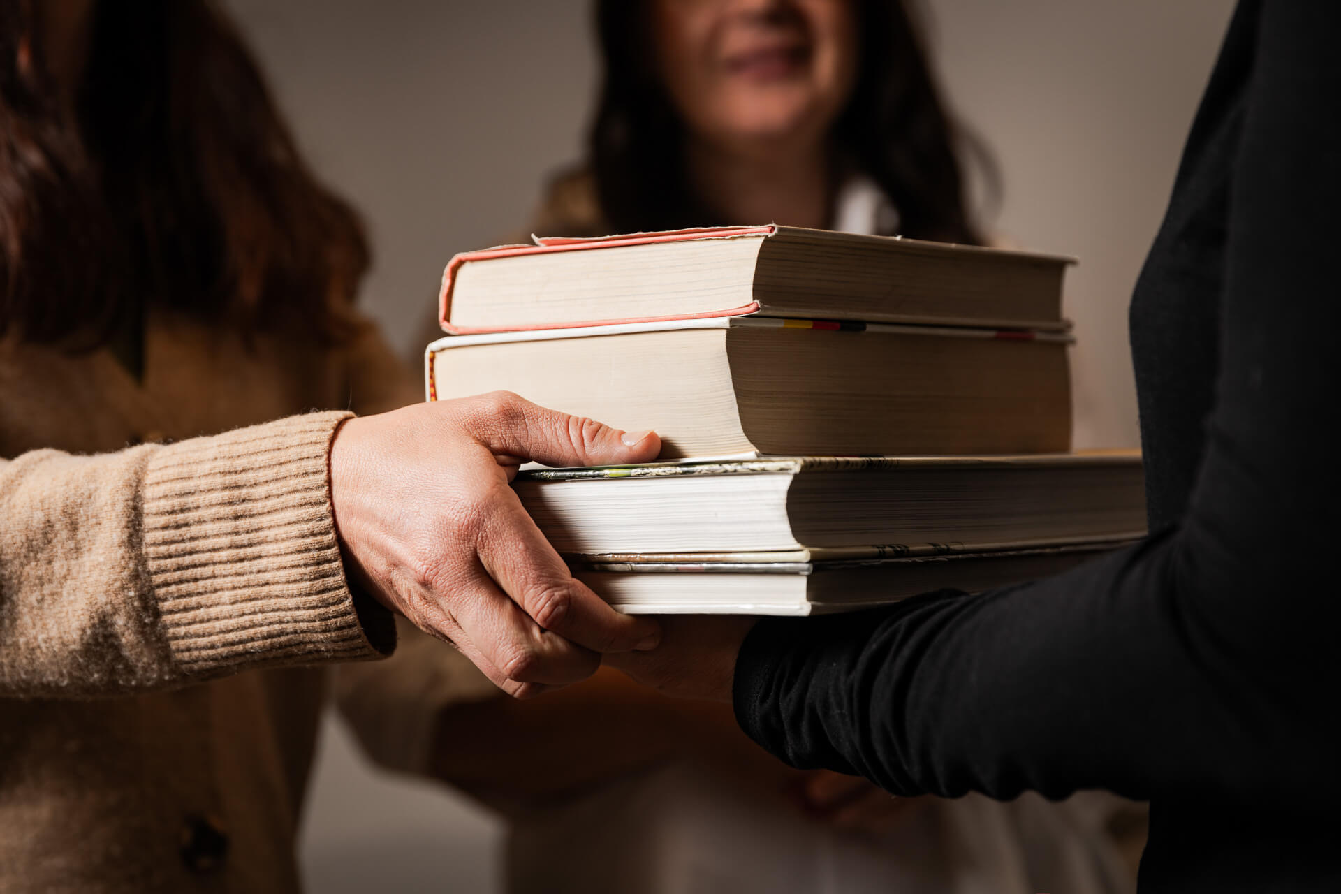 jemand überreicht jemand anderen seine Altlasten in Form von schweren Büchern